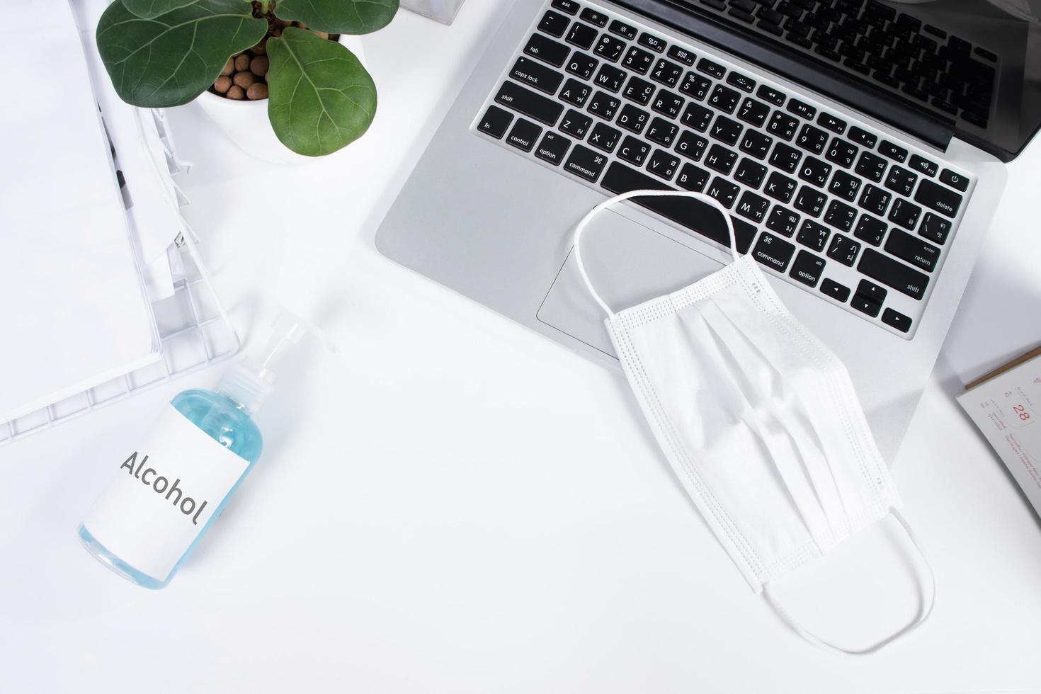 Top view office table desk and workspace with alcohol and protective mask on white background photo