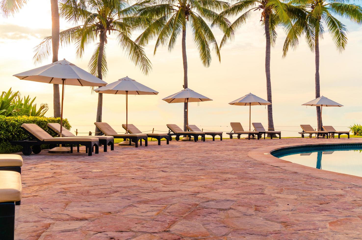 Umbrella and chair around swimming pool in resort hotel for leisure travel and vacation neary sea ocean beach photo