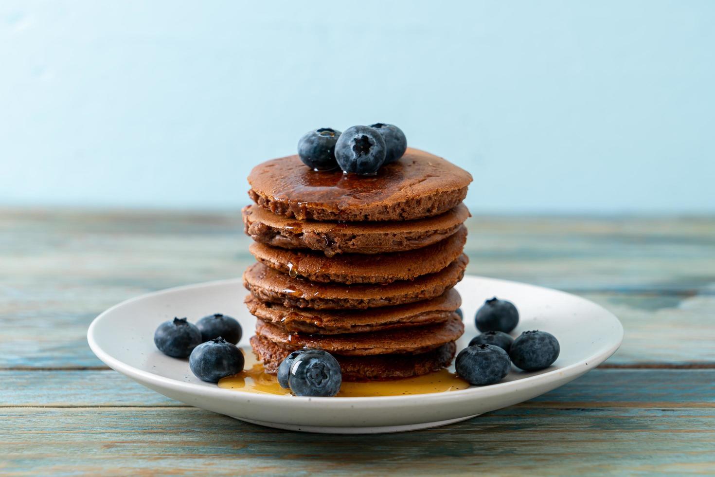 Chocolate pancake stack with blueberry and honey on a plate photo