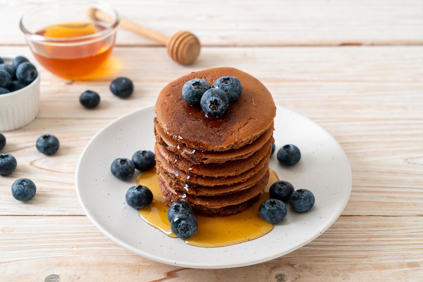 Chocolate pancake stack with blueberry and honey on a plate photo