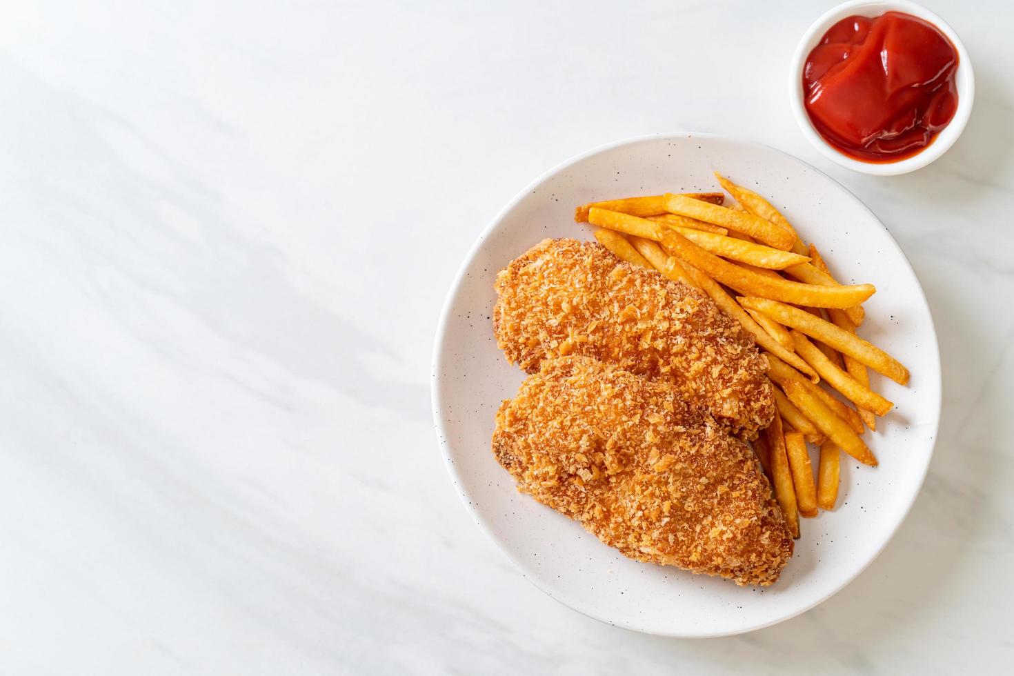 Filete de pechuga de pollo frito con papas fritas y salsa de tomate foto