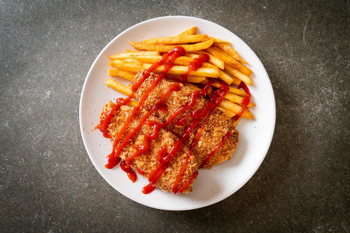 Filete de pechuga de pollo frito con papas fritas y salsa de tomate foto