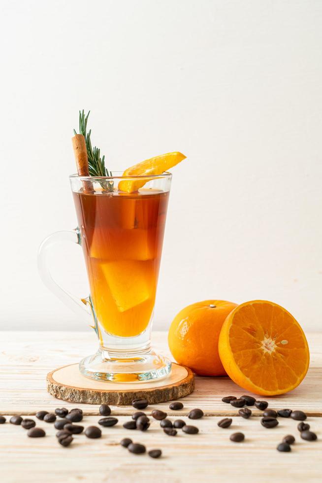 A glass of iced Americano black coffee and a layer of orange and lemon juice decorated with rosemary and cinnamon photo