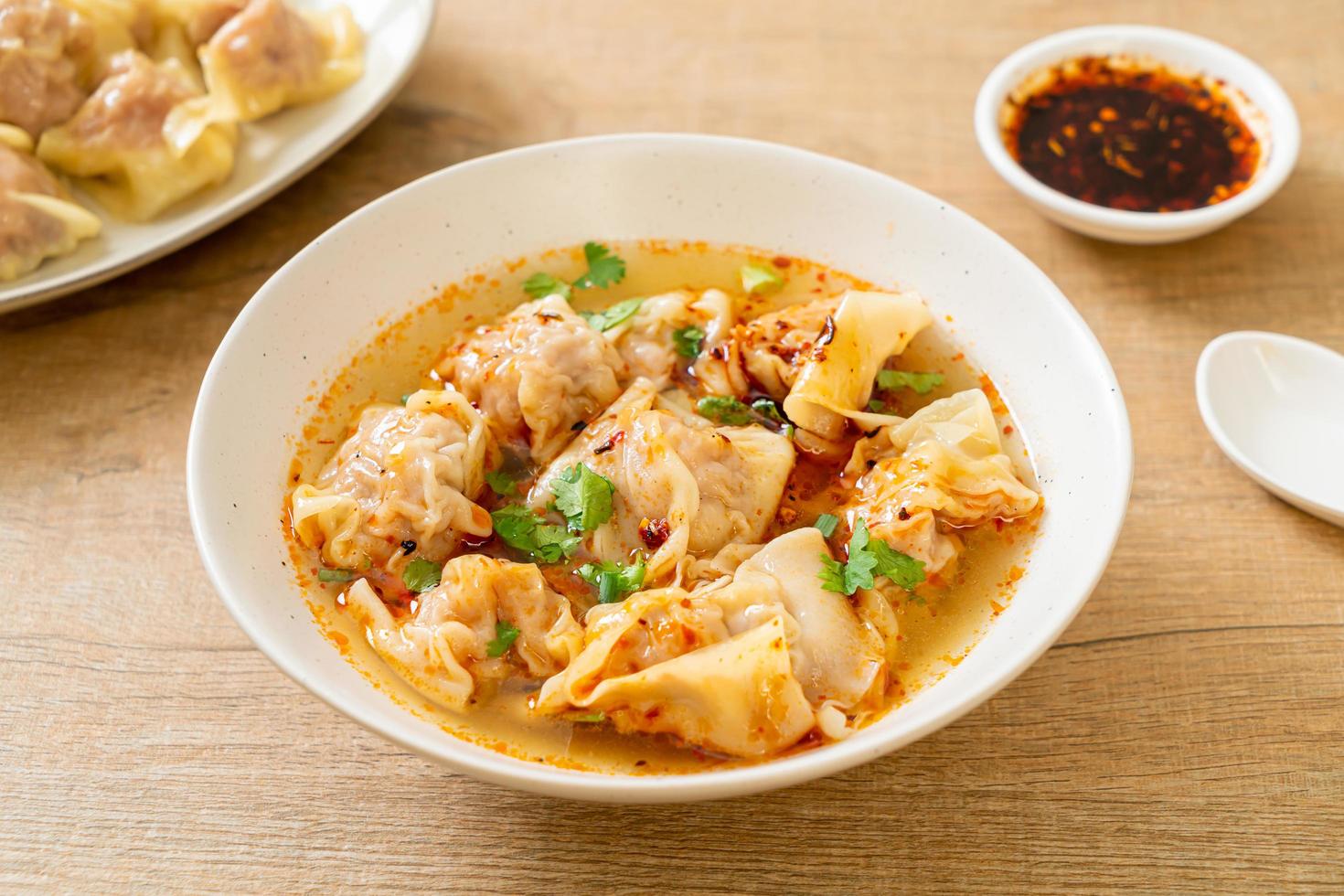 sopa de wonton de cerdo o sopa de albóndigas de cerdo con chile asado - estilo de comida asiática foto