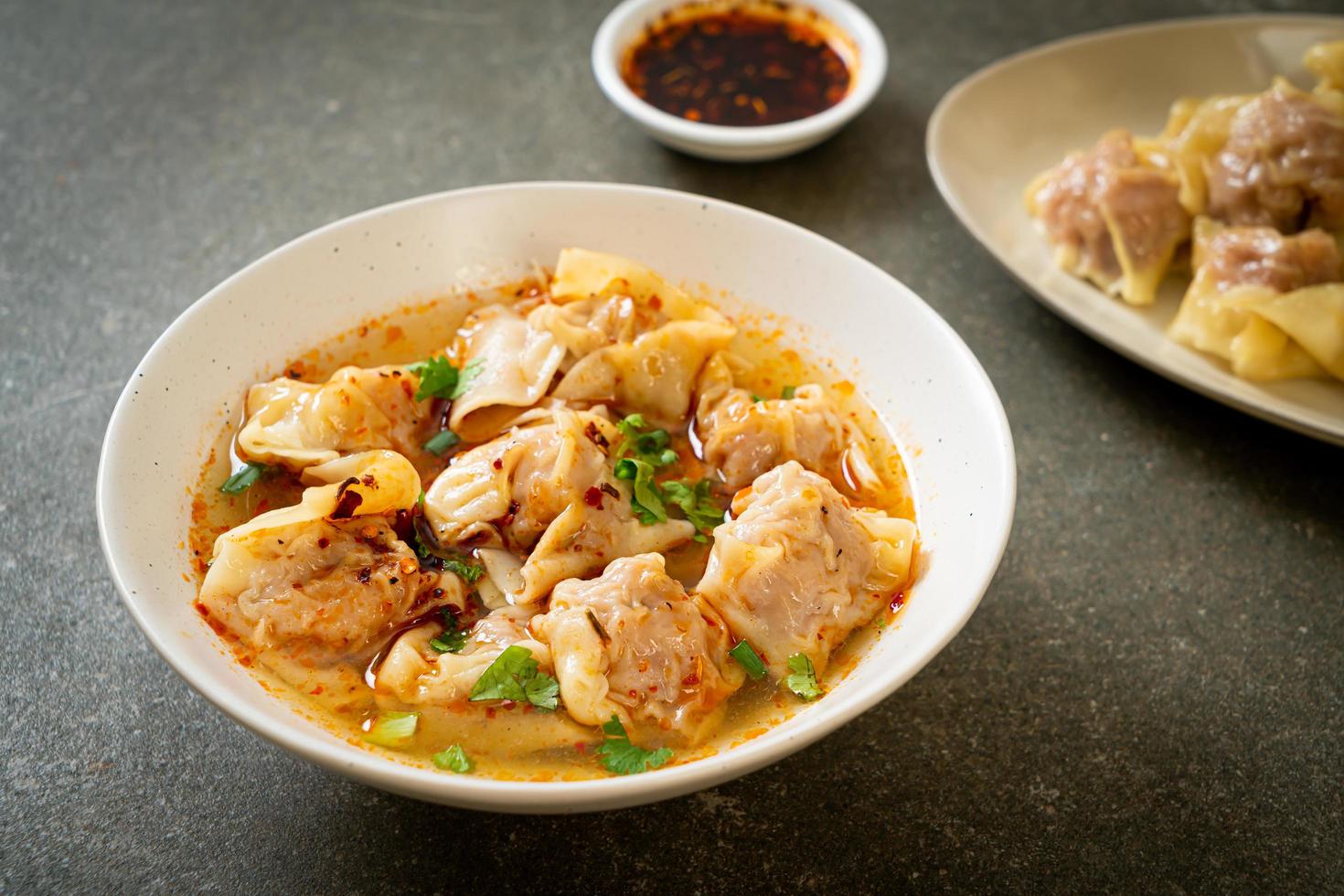 Pork wonton soup or pork dumplings soup with roasted chili - Asian food style photo