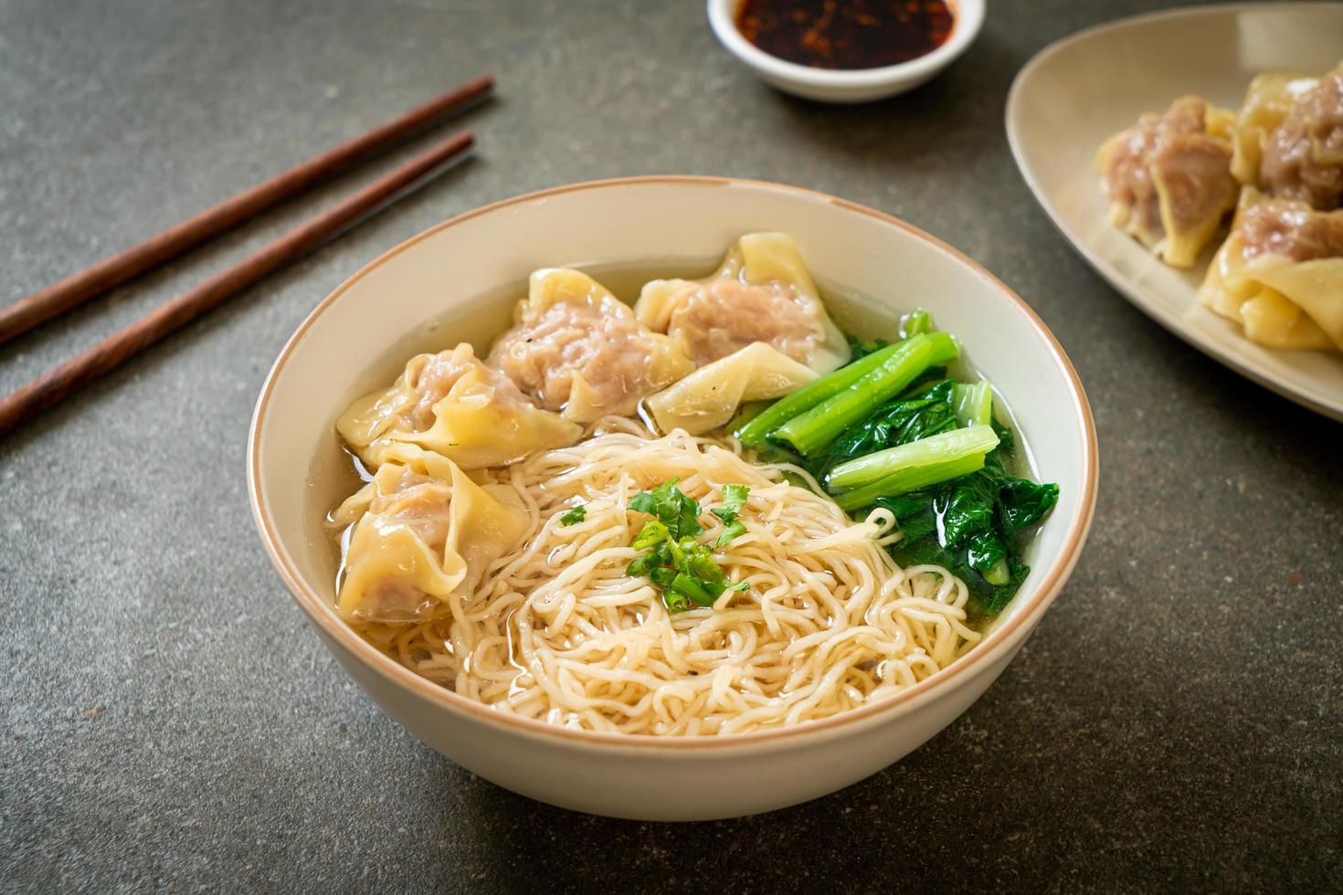 Egg noodles with pork wonton soup or pork dumplings soup and vegetable - Asian food style photo