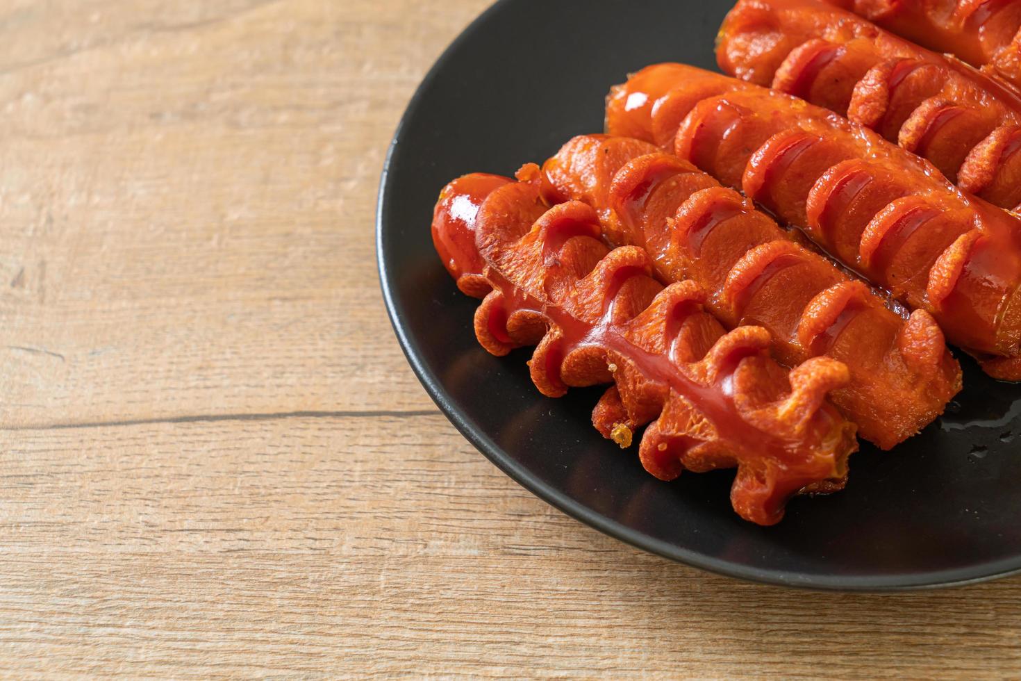 Deep-fried sausage skewer on a black plate photo