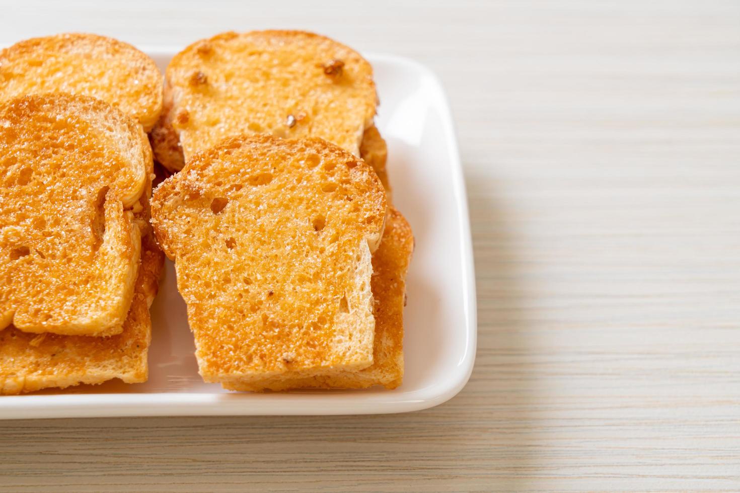 Baked crispy bread with butter and sugar on a plate photo