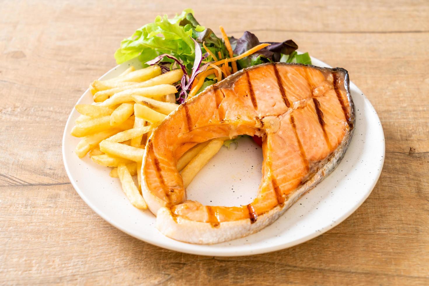 Grilled salmon steak fillet with vegetables and french fries on a plate photo