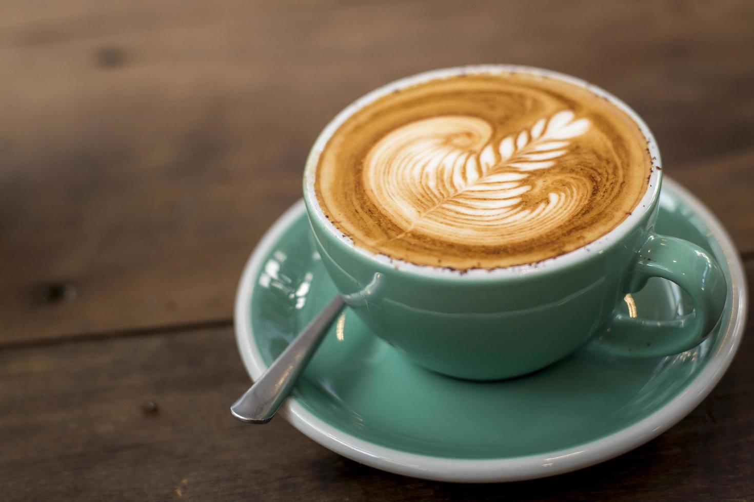 Hot cappuccino with latte art on wood background photo