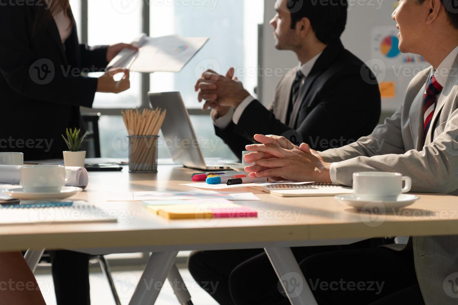 Equipo de negocios multiétnico que incluye personas caucásicas y asiáticas discutiendo sobre un nuevo proyecto en la oficina foto