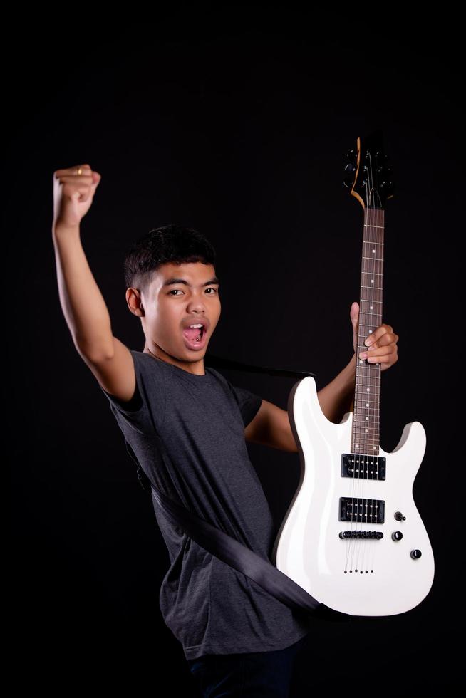 Young man in black leather jacket with electric guitar in studio photo