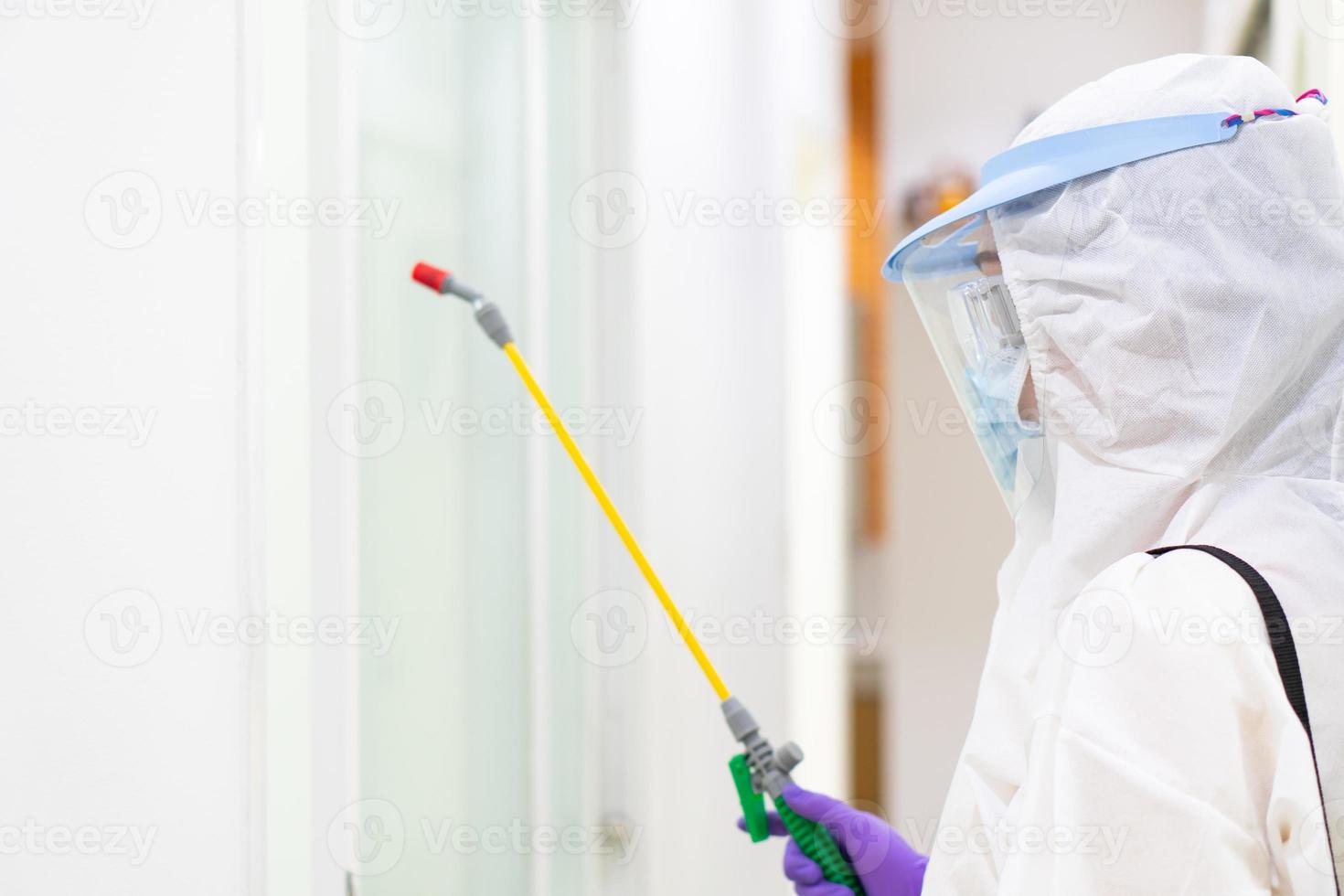 trabajador con equipo de protección personal que incluye máscara de traje blanco y protector facial con desinfectante para controlar la infección por coronavirus foto