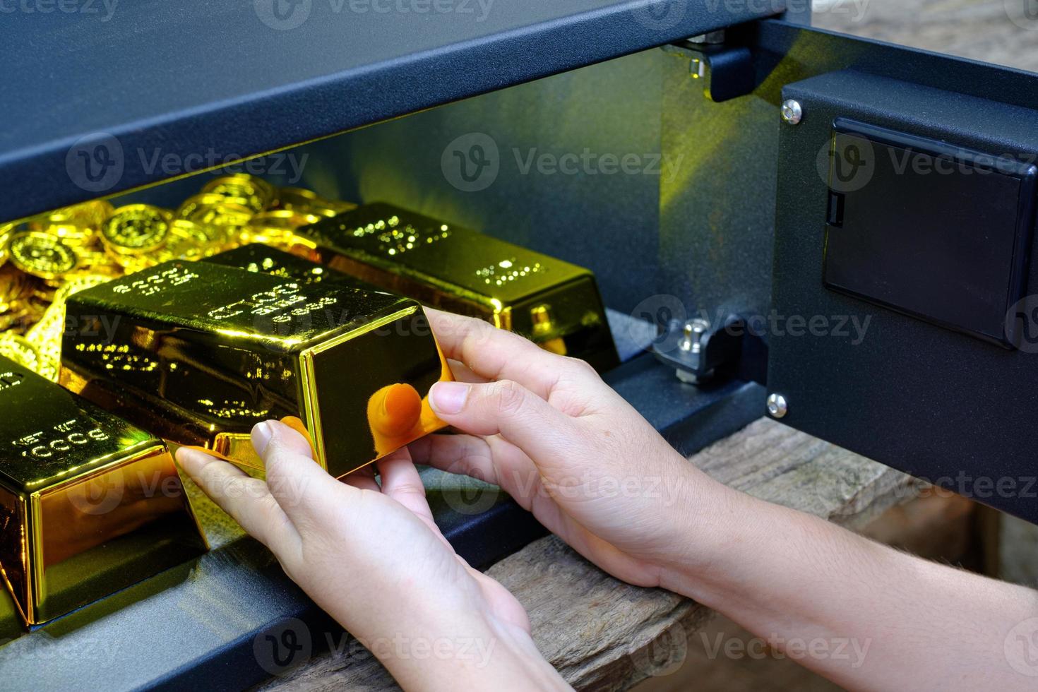 Caja de seguridad de acero electrónica abierta de mano llena de pila de monedas y ba de oro foto