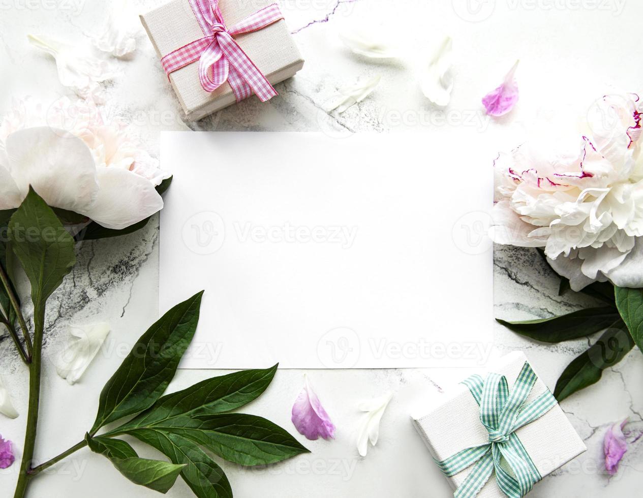 Peonías rosas con tarjeta vacía y caja de regalo sobre fondo blanco. foto