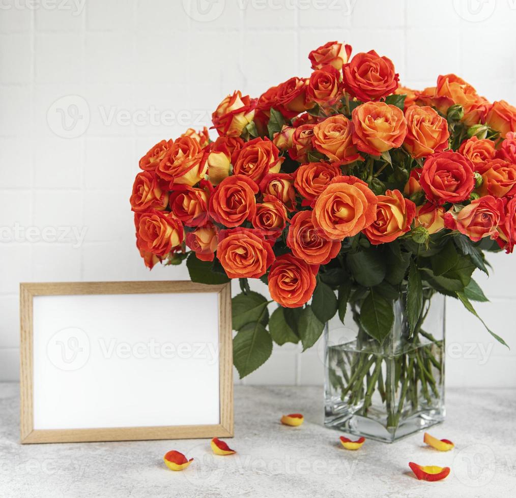 Red roses in a glass vase with an empty photo frame