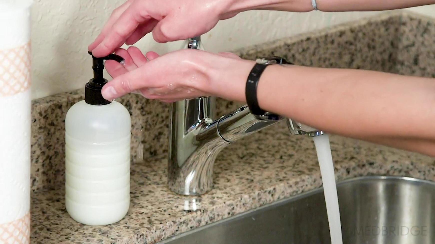 Mujer tomando desinfectante de manos para lavarse las manos de la botella de desinfectante foto