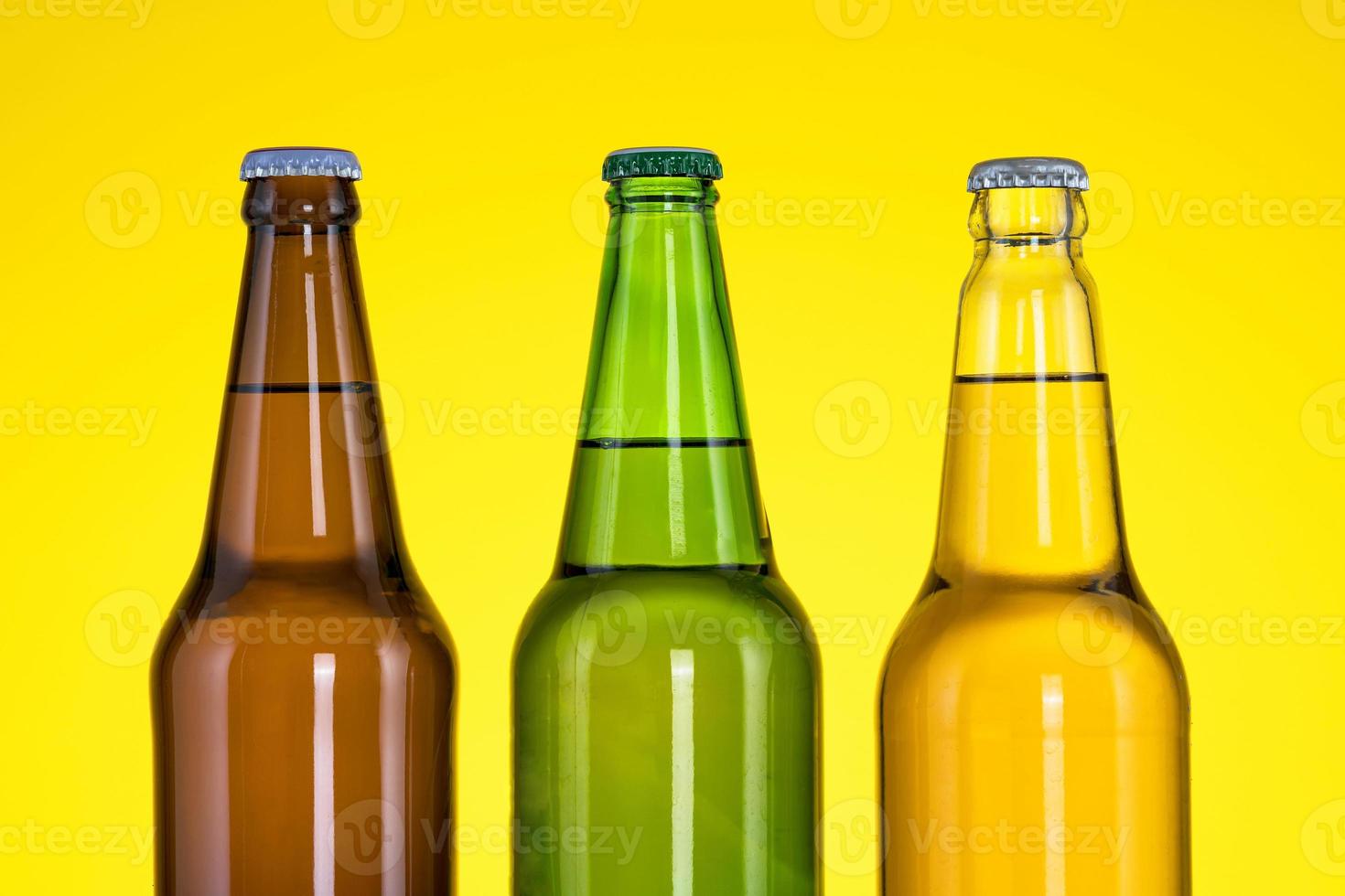 Group of Three bottles of beer isolated on yellow background photo