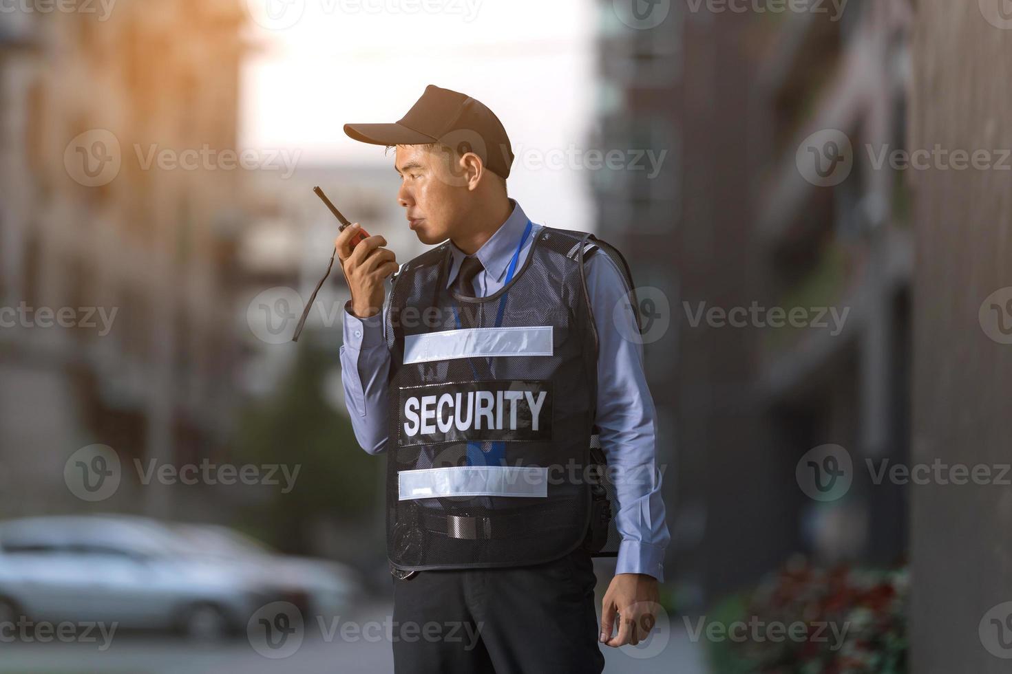 Security man standing outdoors using portable radio photo