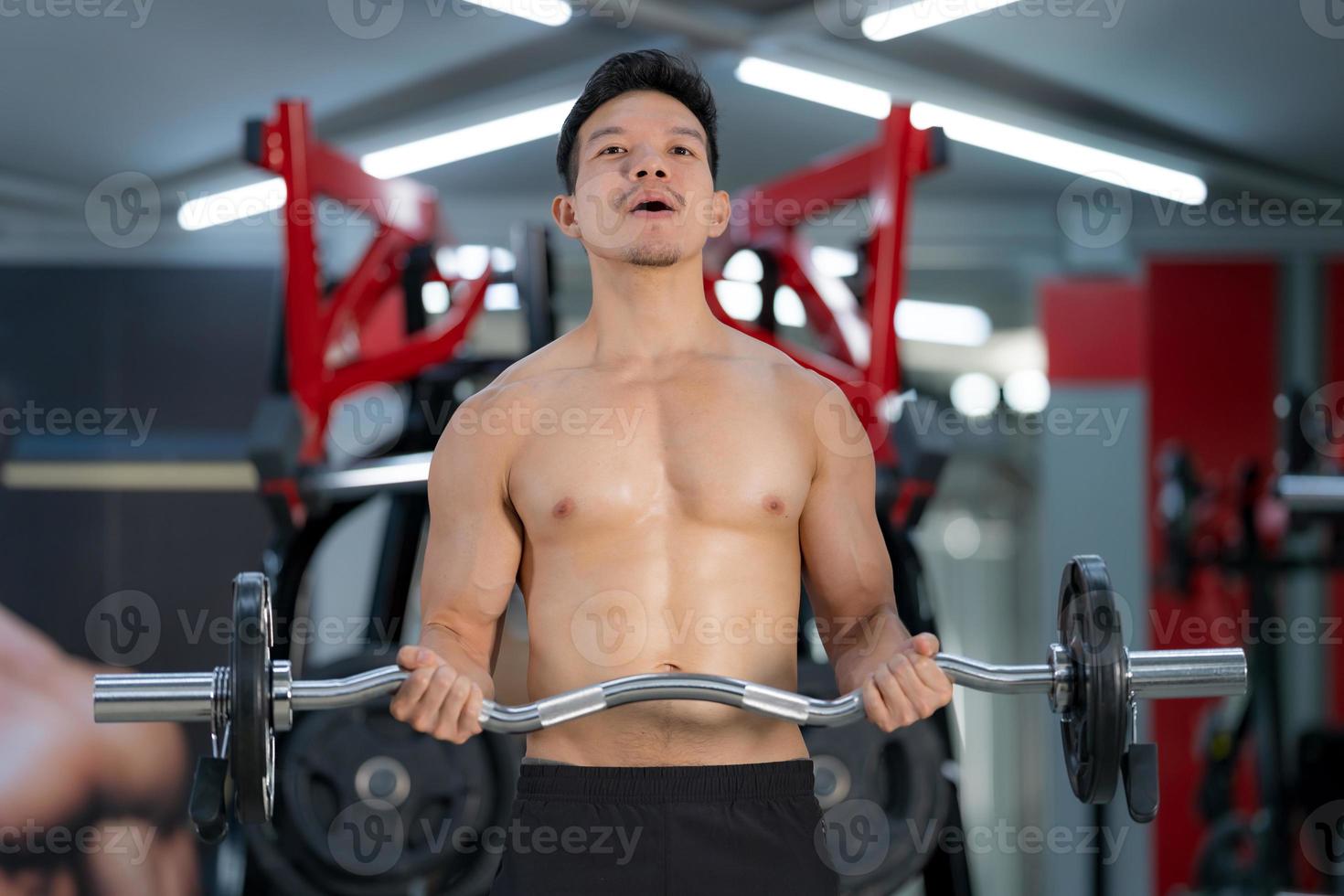 Hombre deportivo entrenando con una barra pesada en el gimnasio. foto