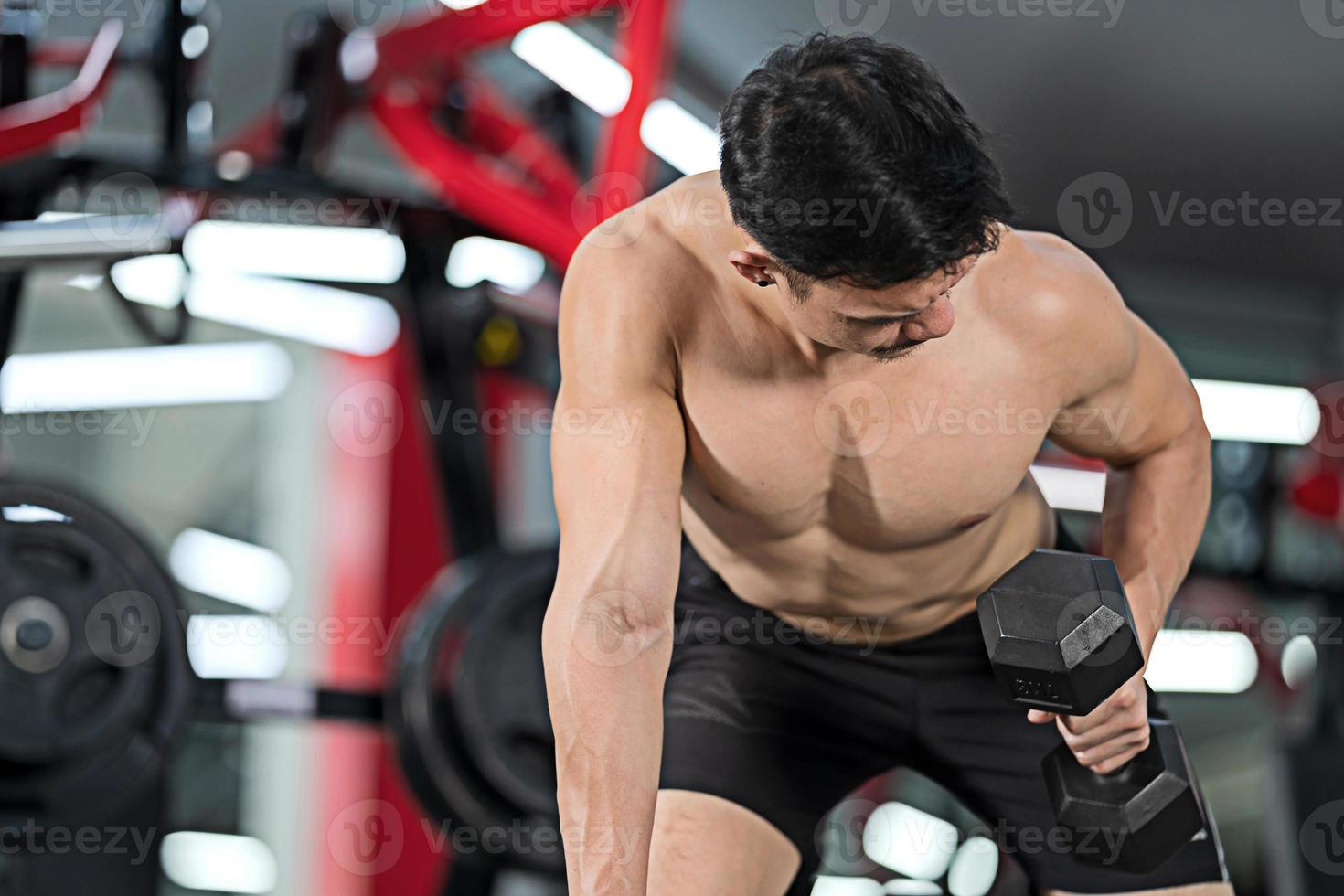 Sporty man training with dumbbell in gym photo
