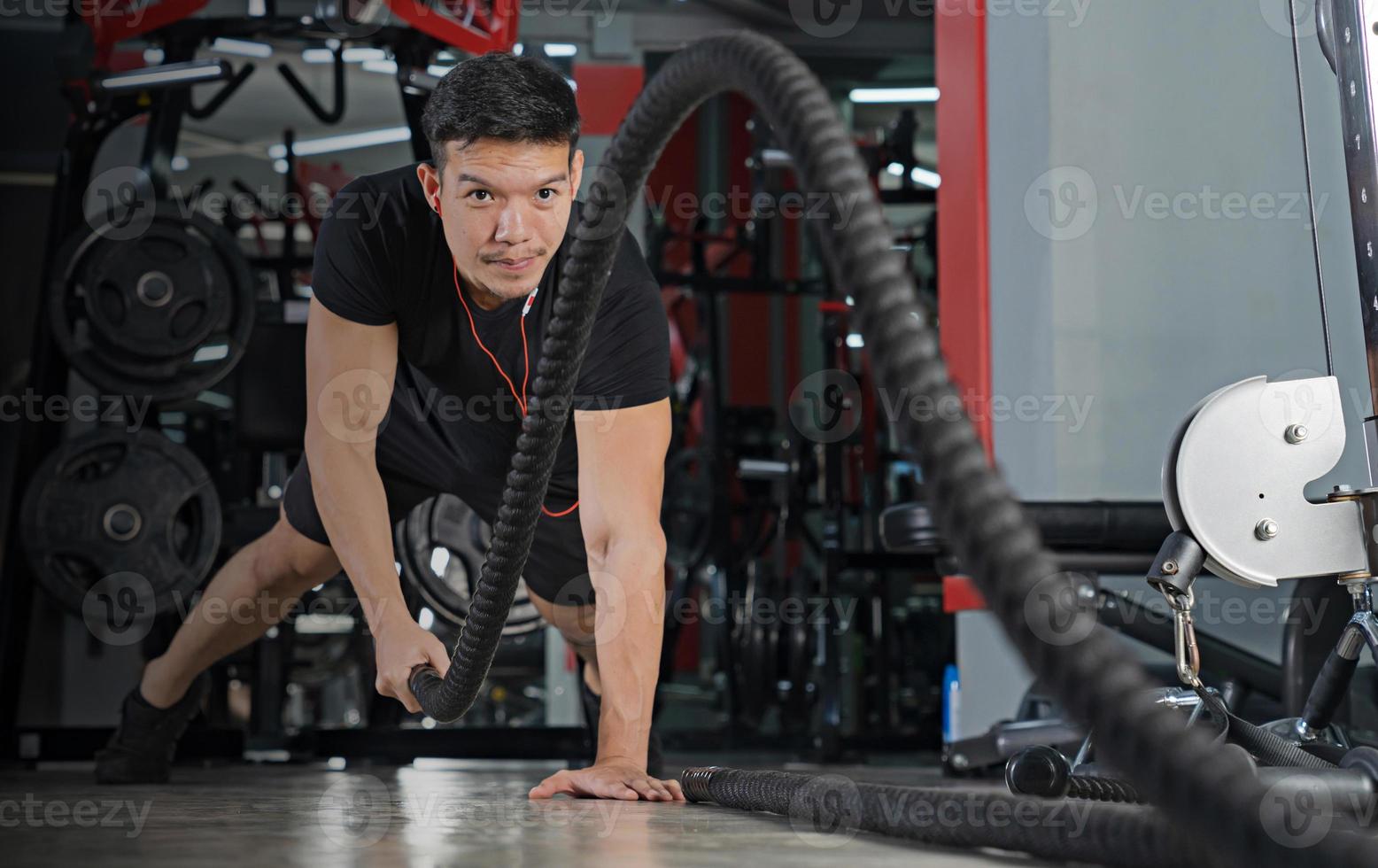 Hombre trabajando con cuerdas de batalla en el gimnasio foto