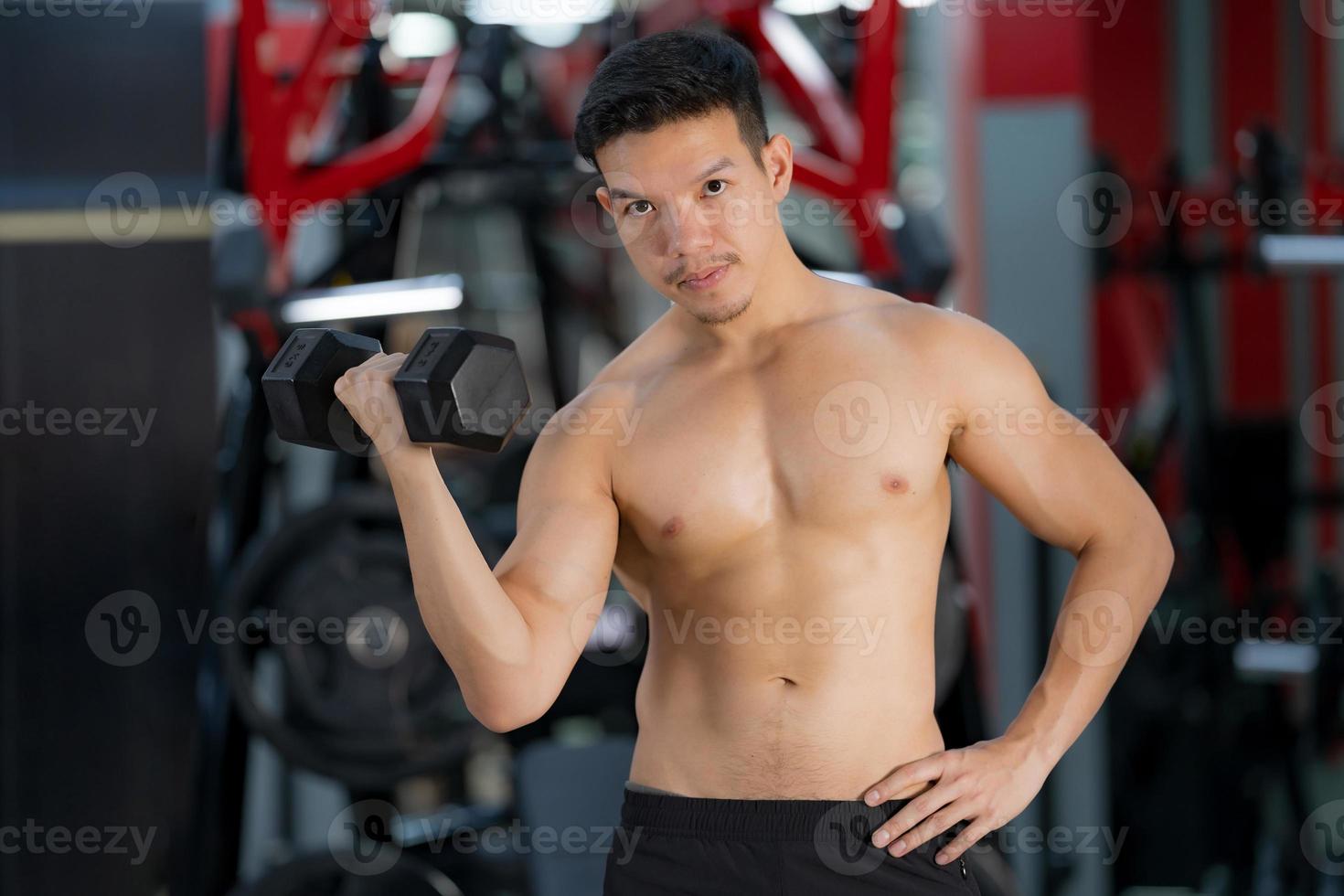 Sporty man training with dumbbell in gym photo