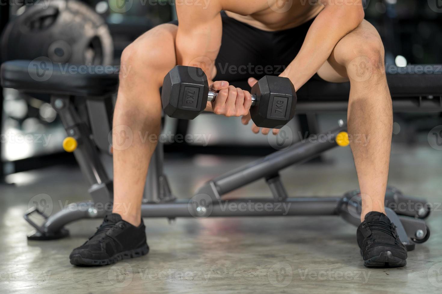 Sporty man training with dumbbell in gym photo