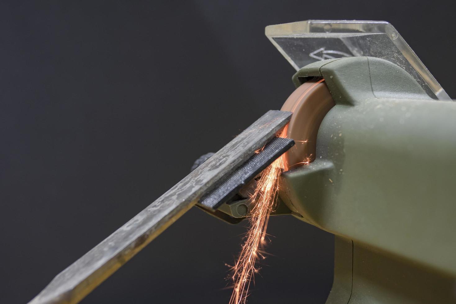 master sharpens a chisel on a grinding machine photo