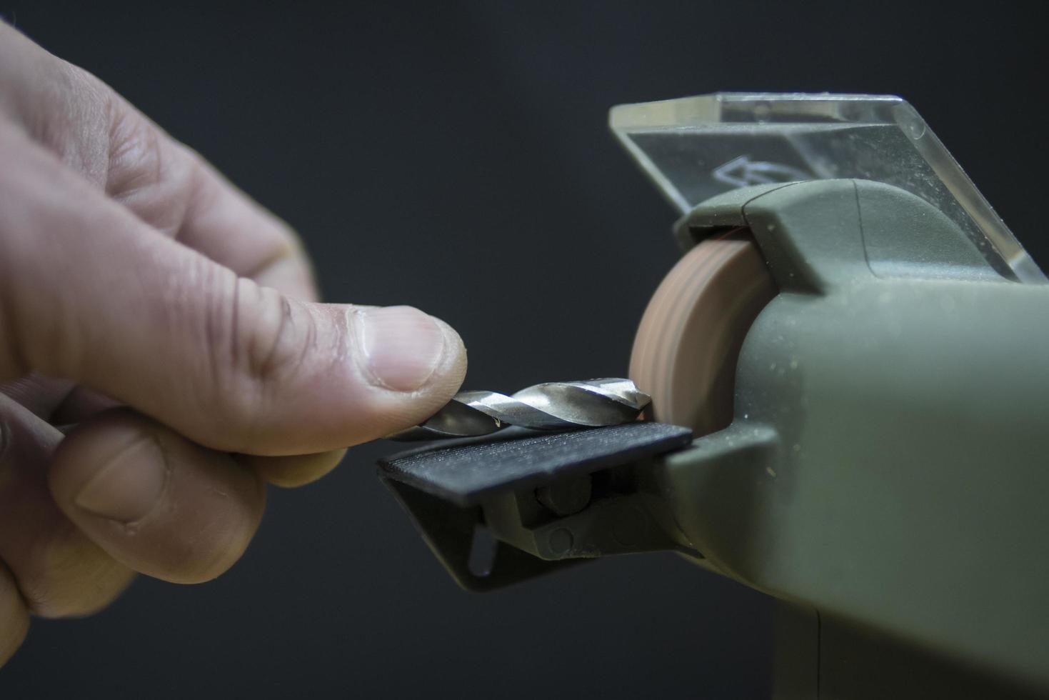 master sharpens the drill on the grinding machine photo