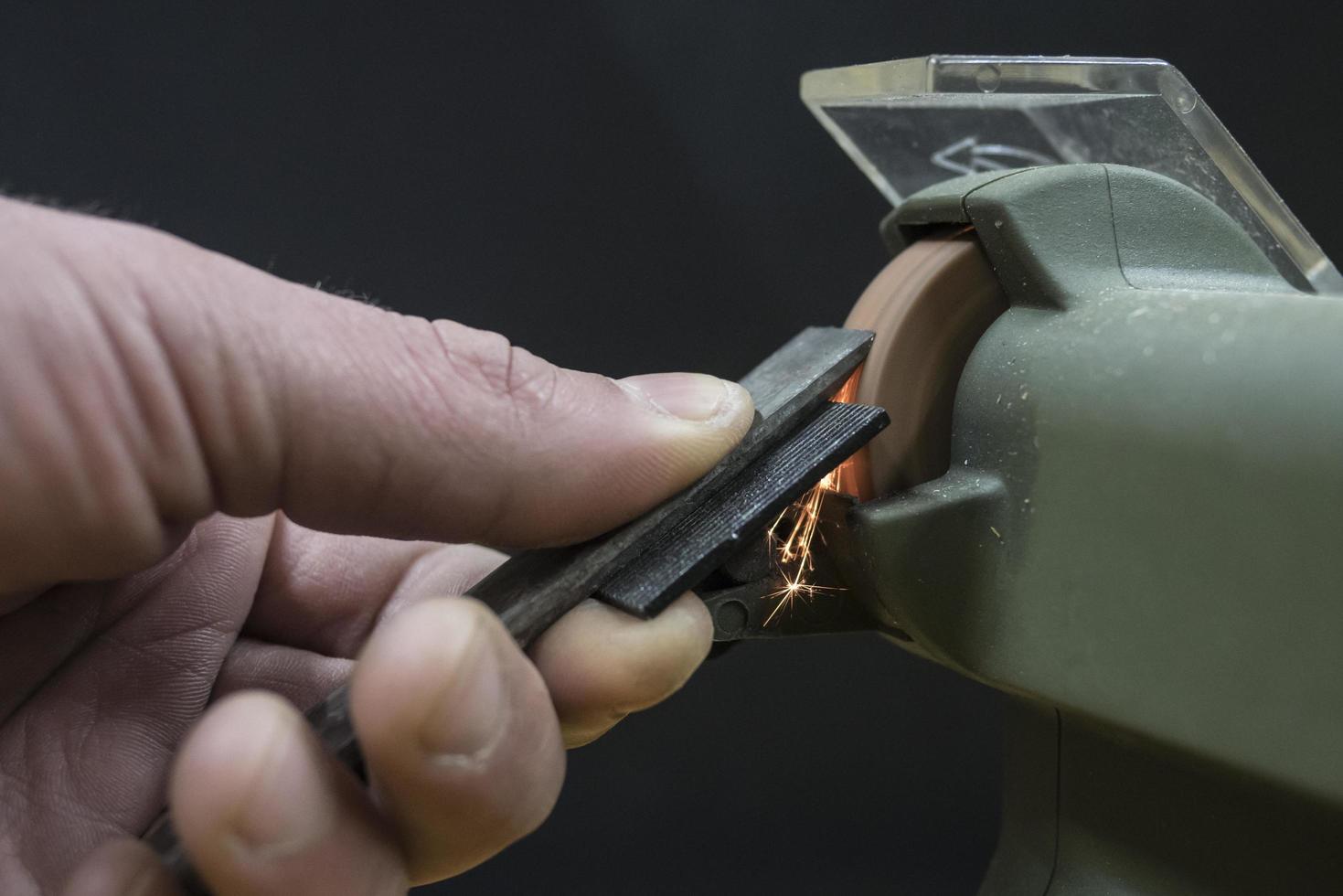master sharpens a chisel on a grinding machine photo
