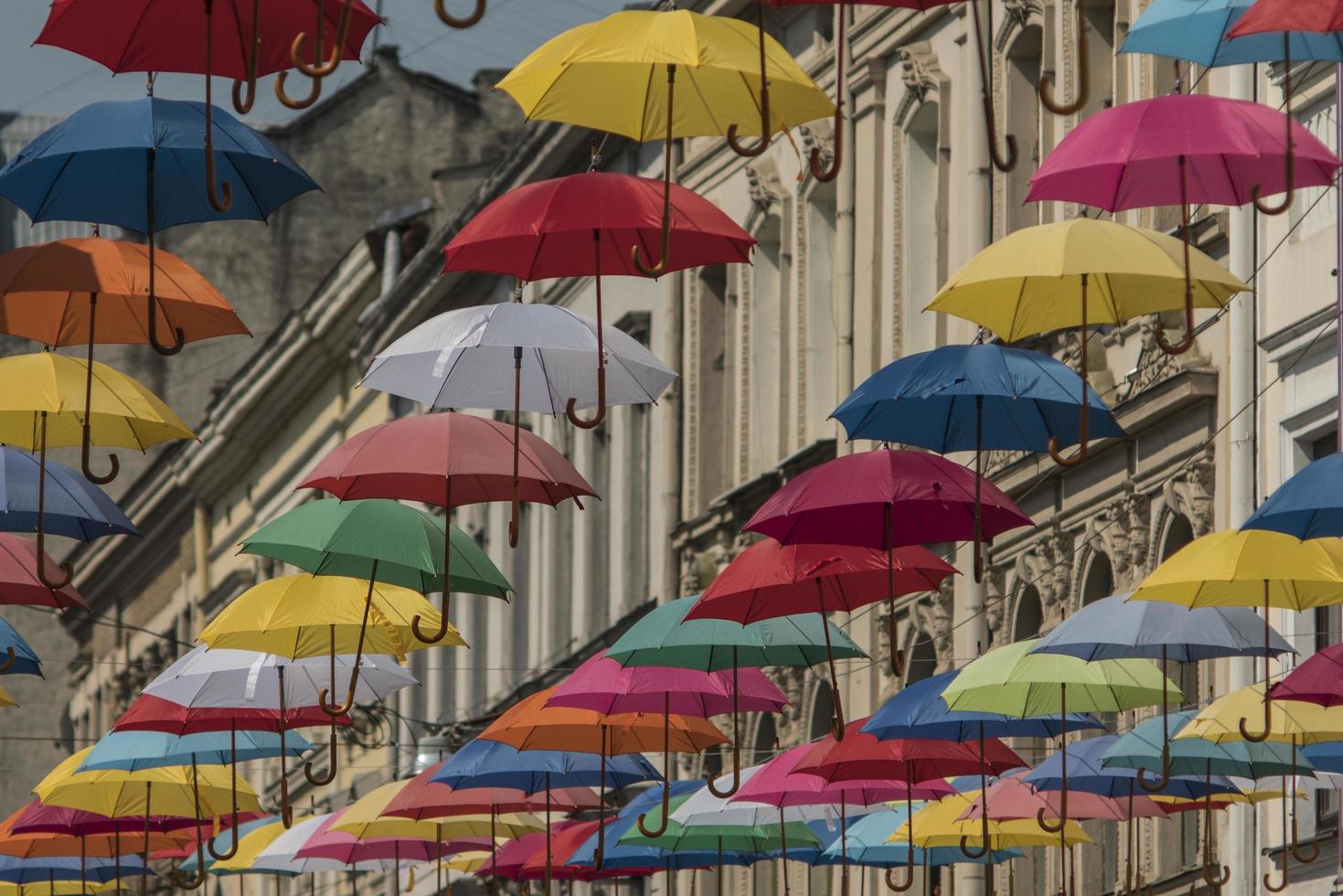 colorful umbrellas hang on the background of the old city in the lviv photo