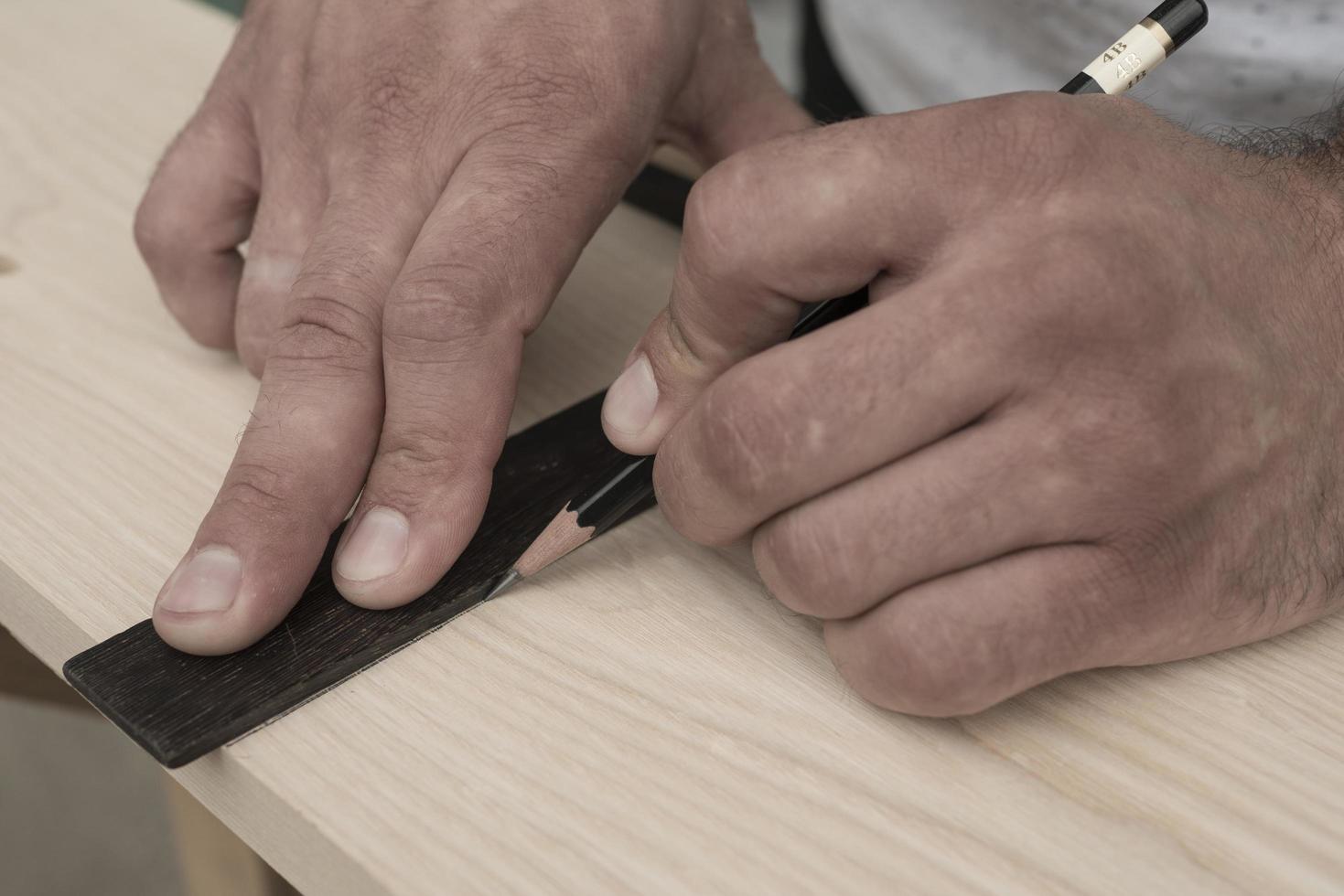 el carpintero marca la pieza de trabajo con un lápiz foto
