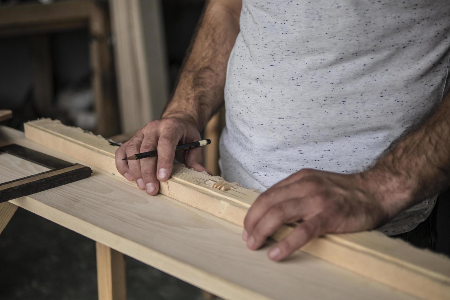 el carpintero marca la pieza de trabajo con un lápiz de carpintería foto