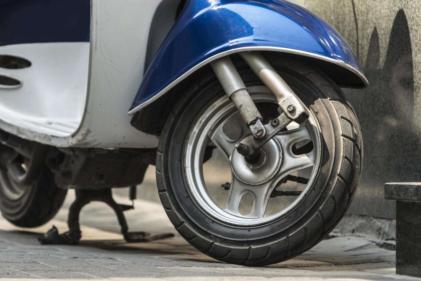 A vintage moped with a blue wing is parked on the sidewalk vintage scooter wallpaper photo