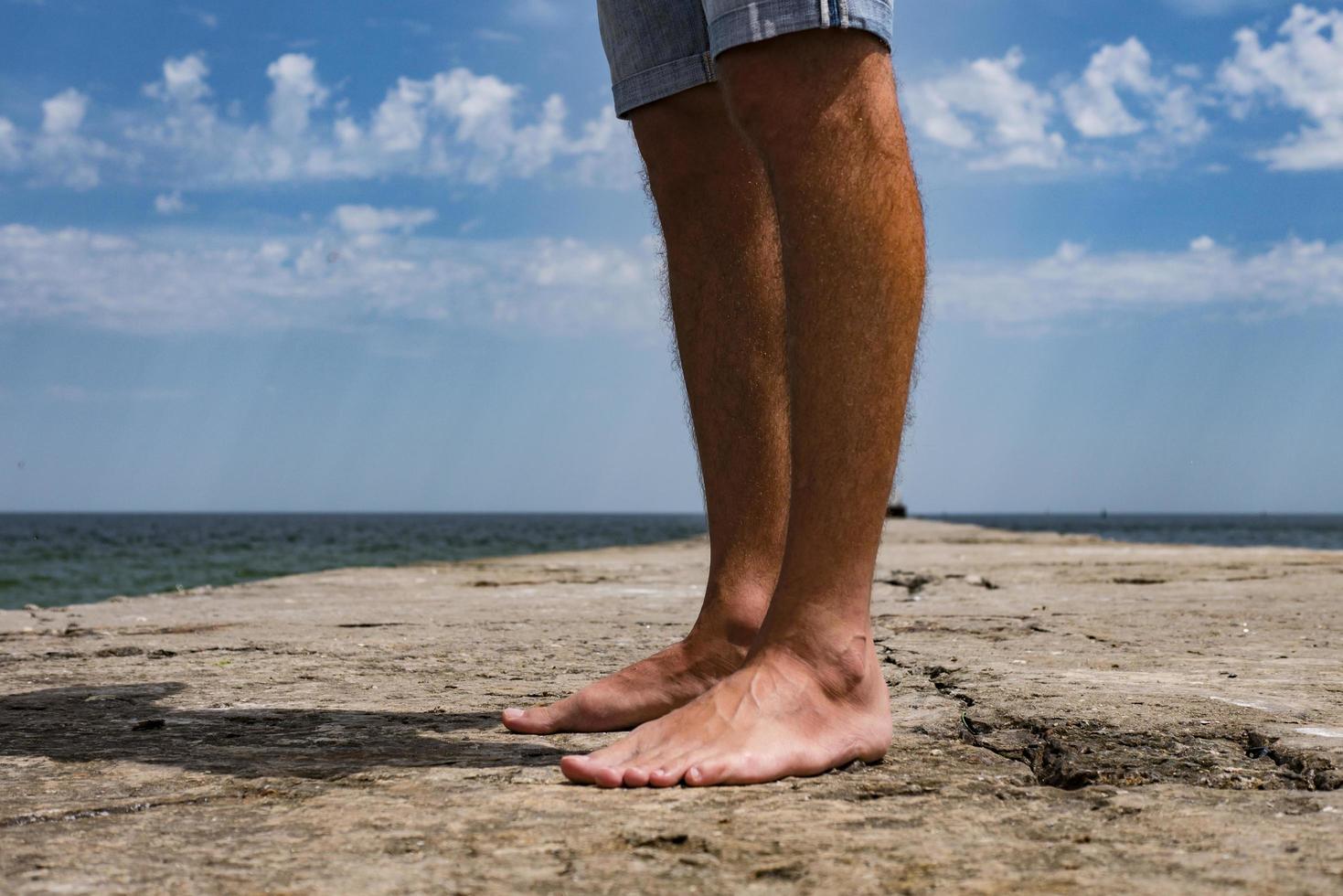 Piernas masculinas en el muelle por el turista de mar de vacaciones foto