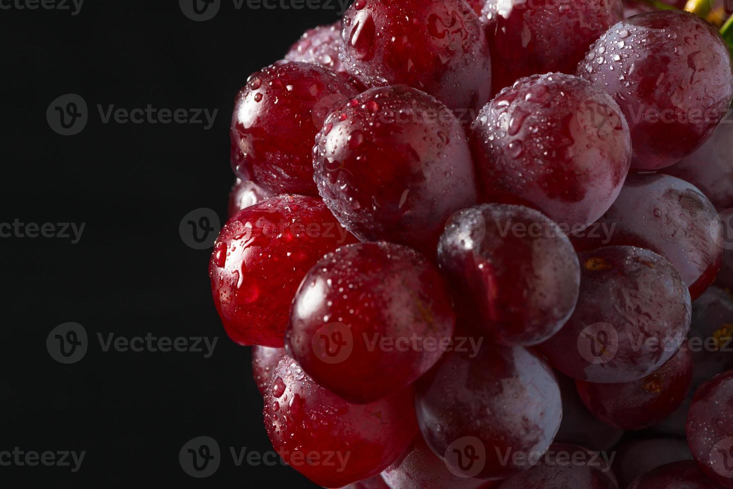 uvas rojas sobre acrílico negro foto