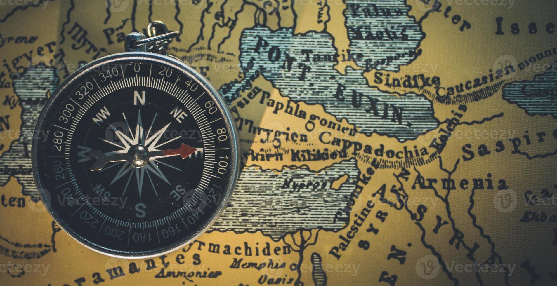 Round gray framed compass on a brown map photo