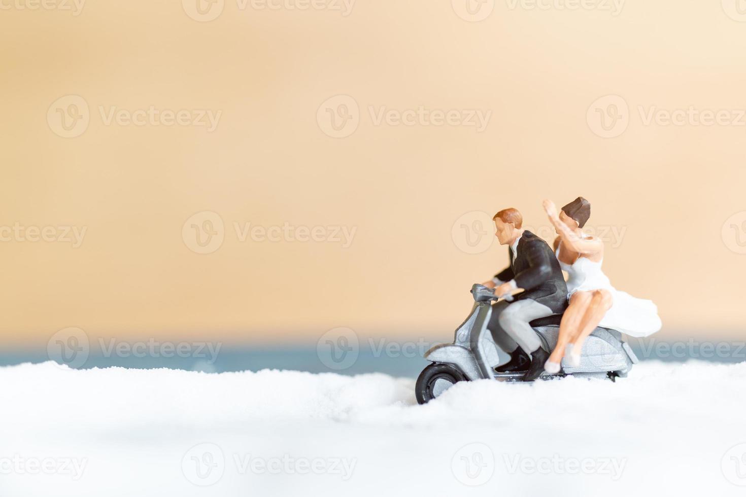 Gente en miniatura, feliz pareja de novios en una playa blanca, concepto de boda foto