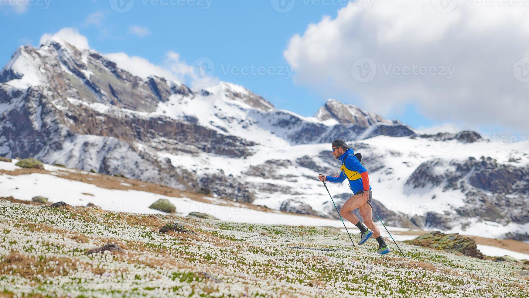 Atleta de pista en las montañas cuesta arriba con palos foto