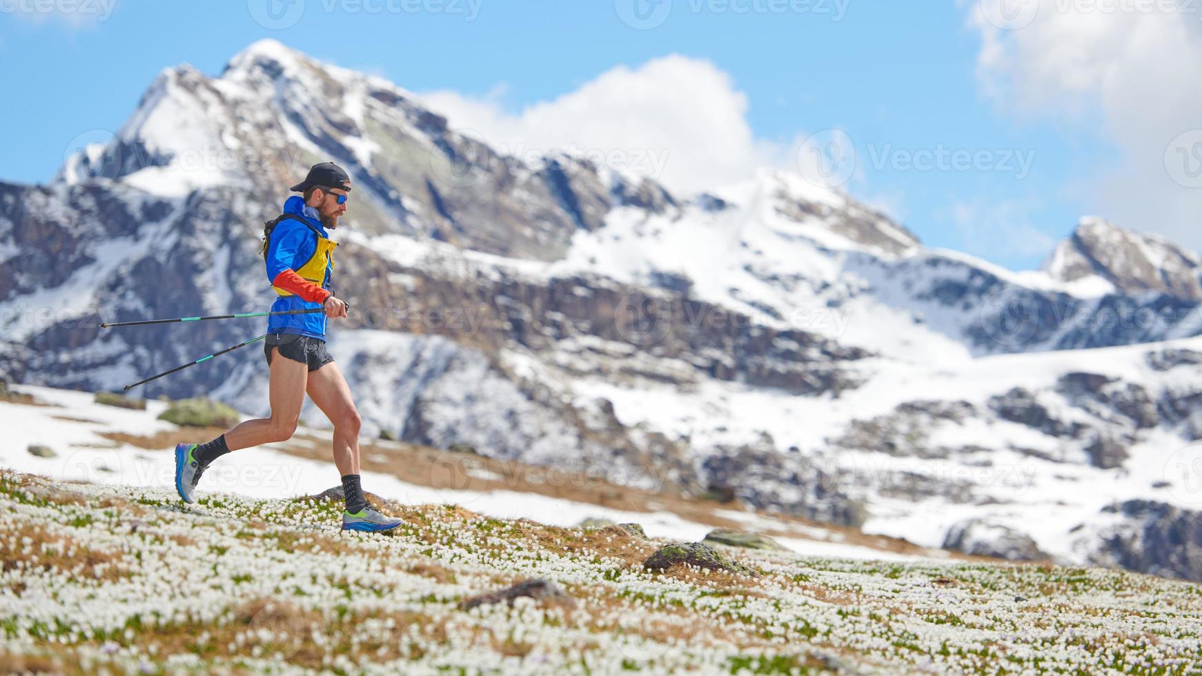 Atleta de pista en montañas cuesta abajo con palos foto