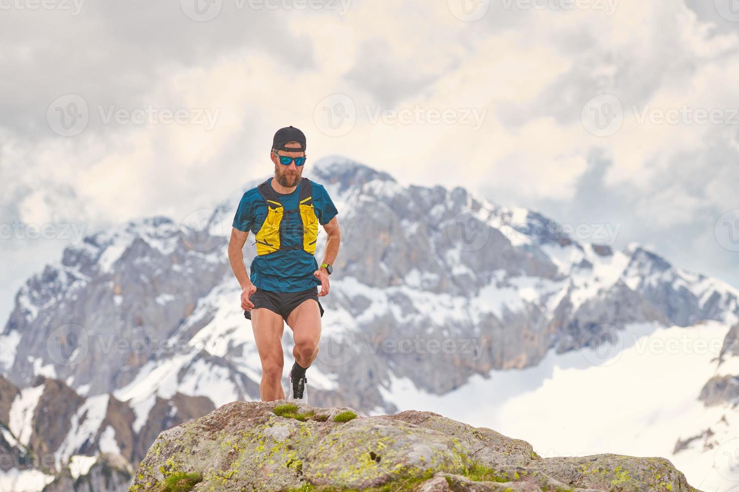 Atleta de trail running en las montañas sobre rocas foto