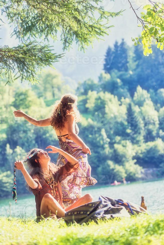 par de chicas hippies junto a un lago se están relajando foto