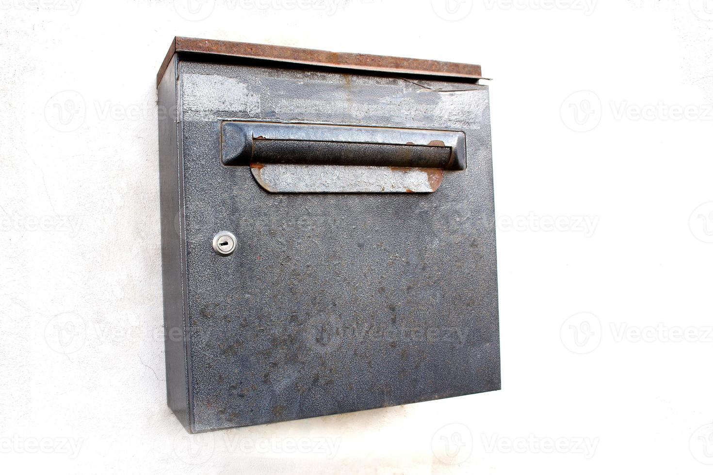 Rusty metal square mail box on white wall background photo