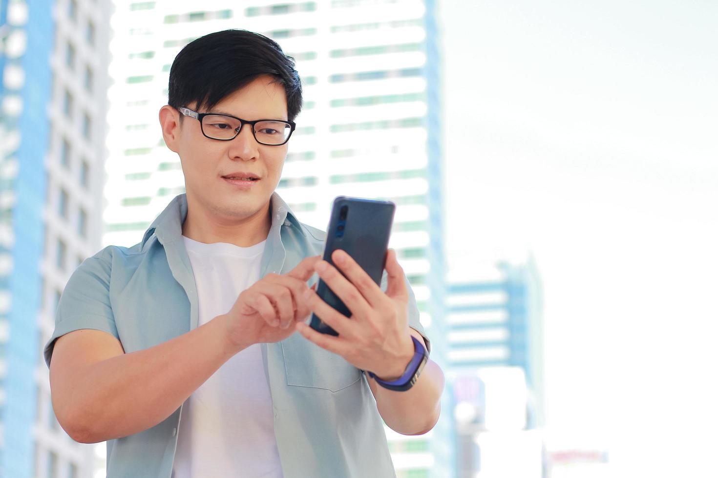 Portrait handsome man is using a smartphone and appears happy There is a building background and modern buildings photo