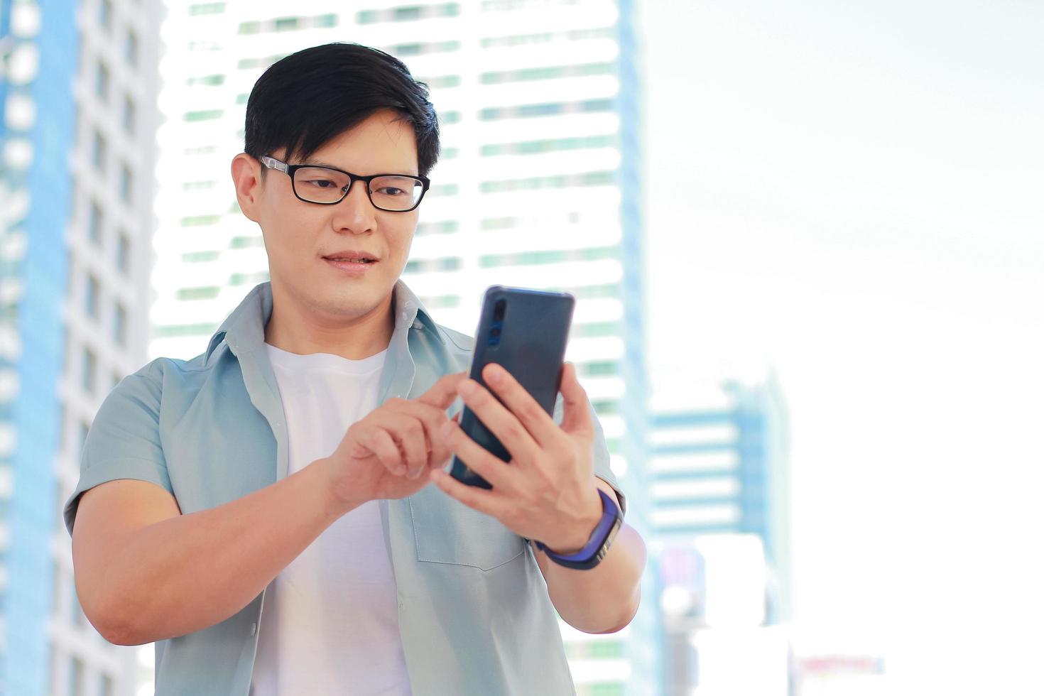 retrato hombre guapo está usando un teléfono inteligente y parece feliz hay un fondo de construcción y edificios modernos foto