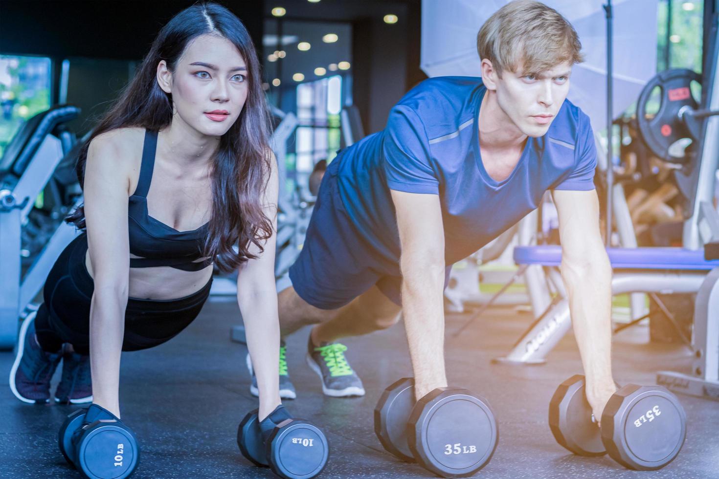 Hermosa mujer asiática está haciendo ejercicio en un gimnasio con un entrenador personal guapo concepto de fitness para la salud foto