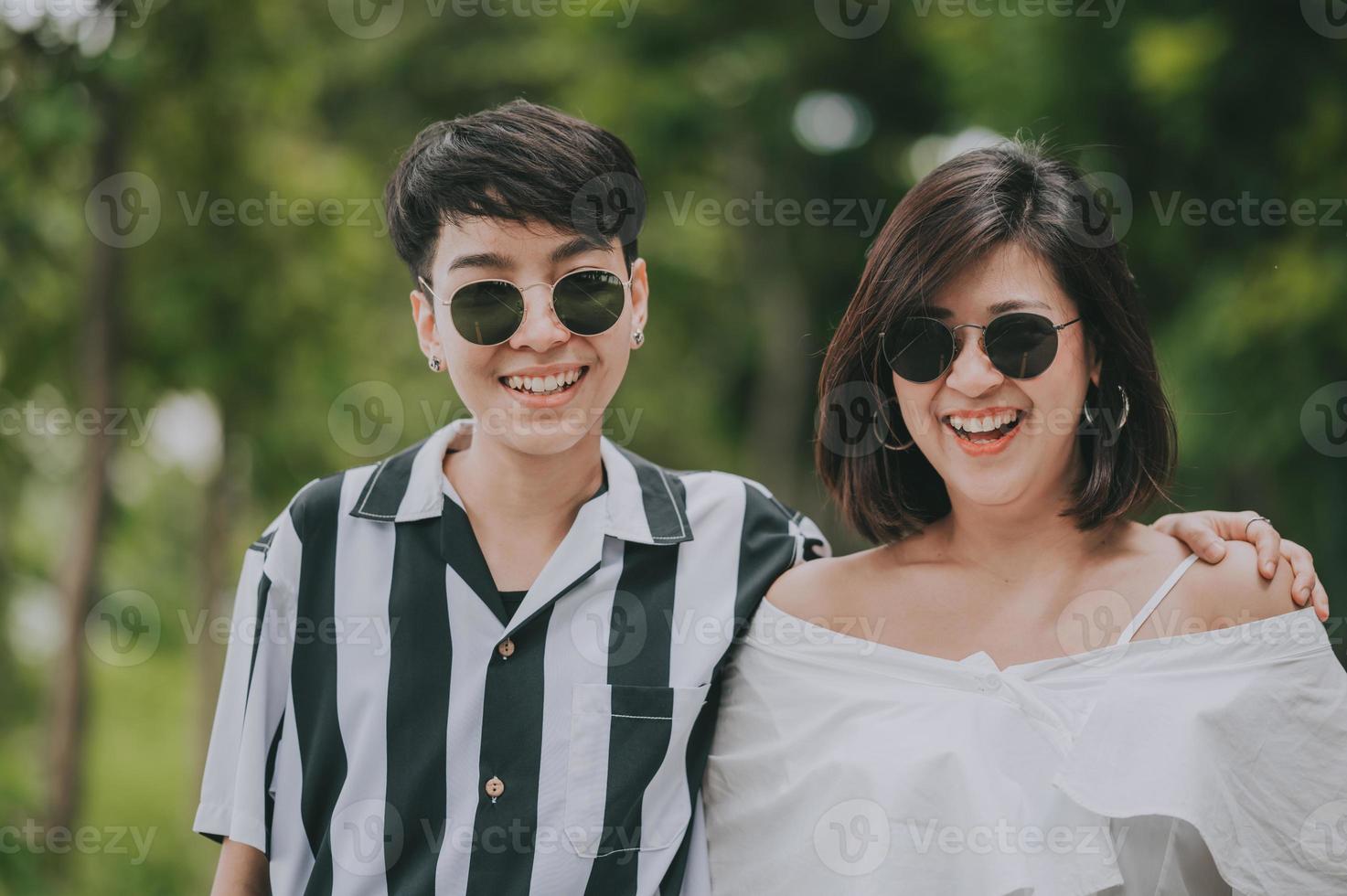 Feliz pareja de lesbianas lgbt asiáticas enamoradas pasando un buen rato de pie y abrazándose en el parque foto