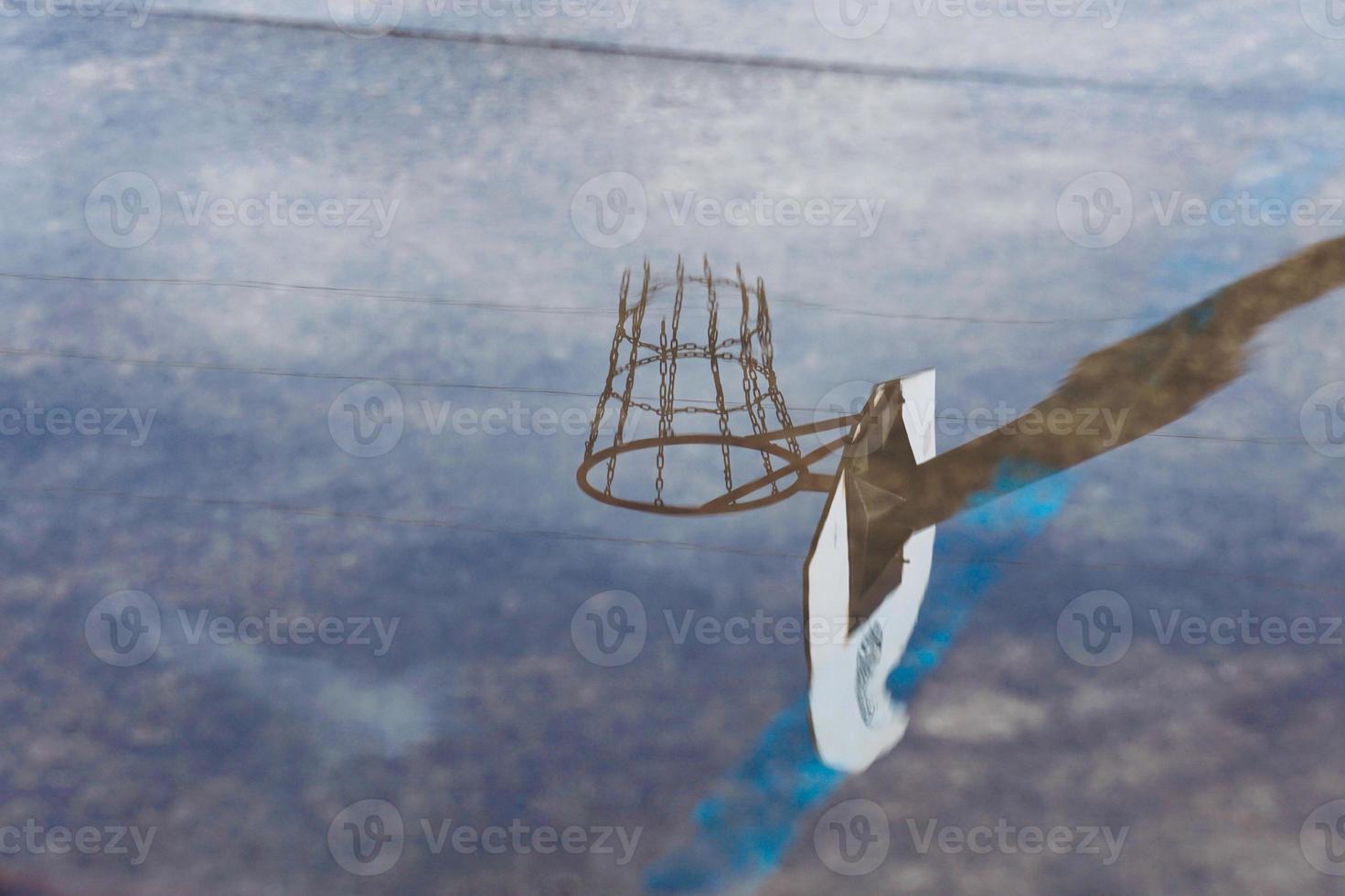 street basketball hoop reflected on the puddle photo