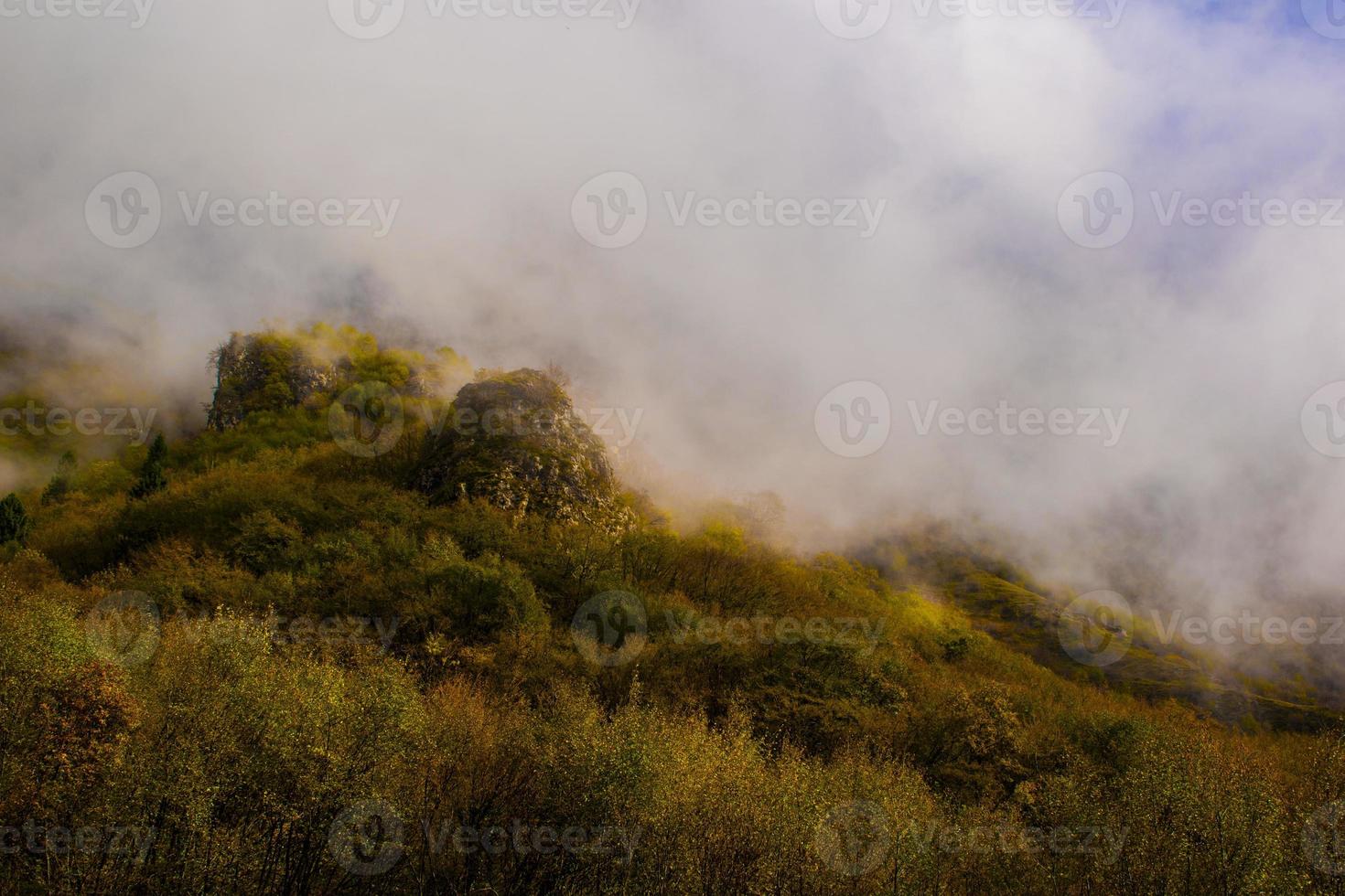 Fog rising above hill photo